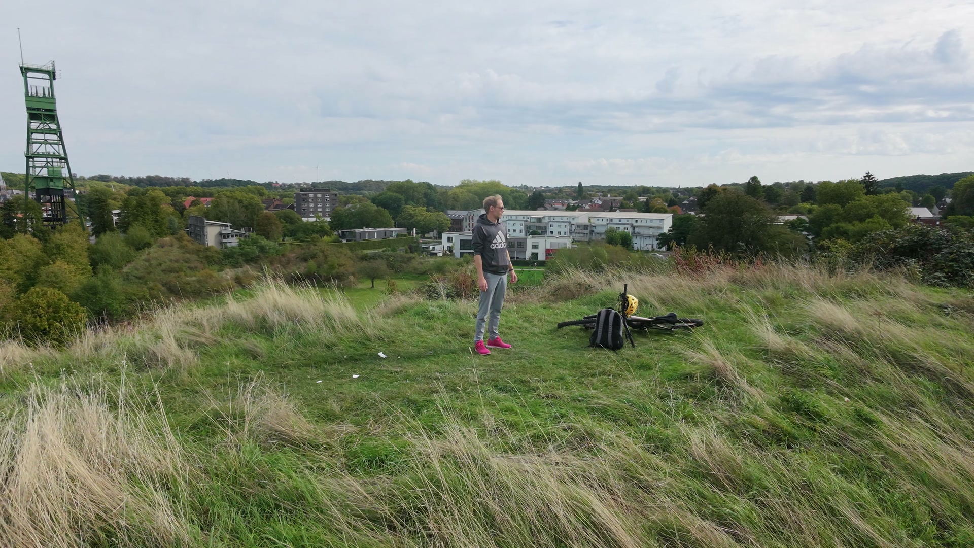 Jens steht mit seinem eMTB auf einer grasbewachsenen Anhöhe, die Drohne kreist um ihn
